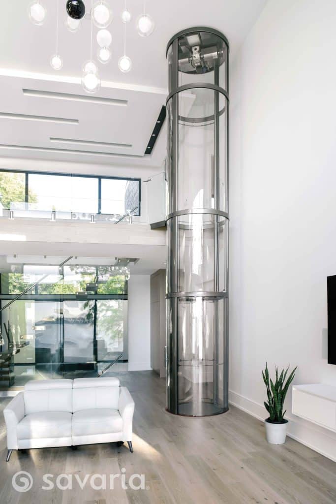 Modern living room with a transparent glass elevator and a white sofa.